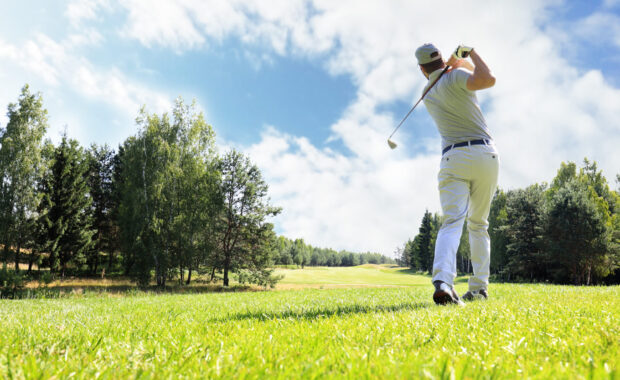 Golfer mid-swing on a sunny fairway